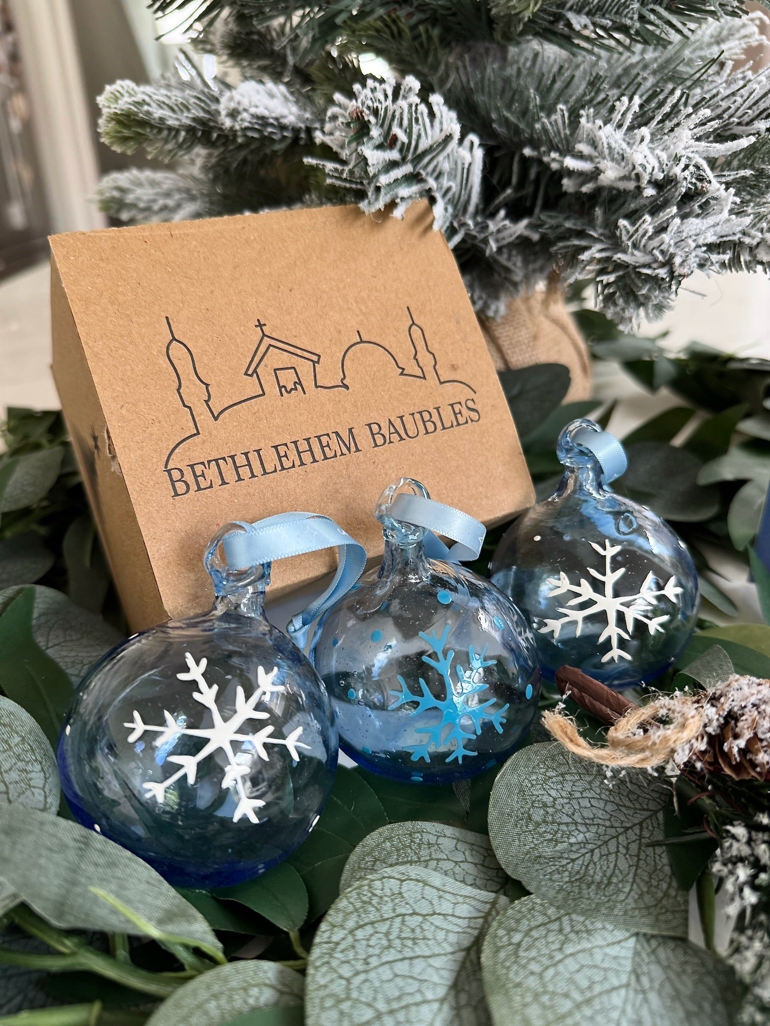 Decorative Christmas ornaments with snowflake designs in front of a 'Bethlehem Baubles' box.